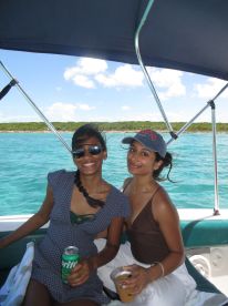 Two friends enjoy drinks and laughter on a boat, surrounded by stunning turquoise waters — a perfect moment for a fun day out on the water.