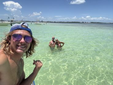 A group enjoys a sunny day swimming in crystal-clear waters, capturing the essence of fun and relaxation on a beach outing.