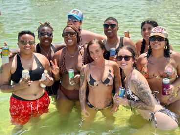 A lively group of friends enjoys a fun day in the water, celebrating with drinks and laughter — perfect for summer outings and beach parties.