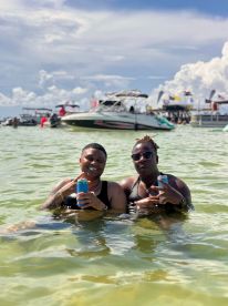 Two friends enjoy a fun day in the water, celebrating with drinks amidst a lively boating scene — perfect for summer parties and aquatic adventures.