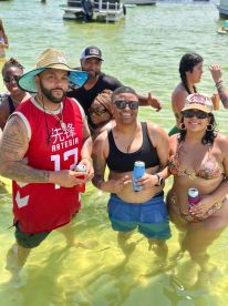 A lively group enjoys a fun day in the water, holding drinks and celebrating together — perfect for summer outings and beach parties.