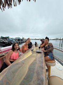 A lively group of friends enjoys drinks on the deck of a boat, perfect for social gatherings and celebrations on the water.