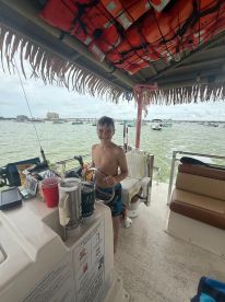 A young boy stands at the helm of a boat, enjoying the interior space with life jackets overhead and drinks at hand — perfect for family outings on the water.
