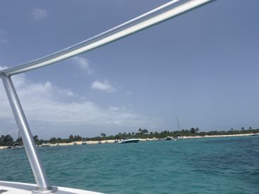 A scenic view of boats anchored near a sandy beach, showcasing the vibrant turquoise waters and lush greenery — perfect for a relaxing day on the water.