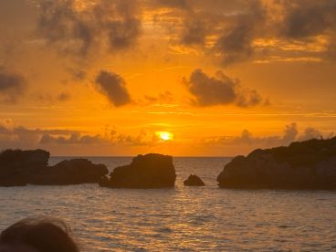 A stunning sunset over rocky outcrops, creating a picturesque backdrop for evening boat cruises and island adventures.