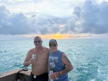 Two friends enjoy drinks while watching a beautiful sunset on the water, capturing the essence of a perfect boating experience.