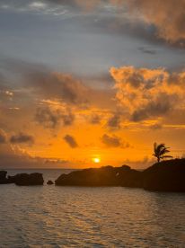 A breathtaking sunset over the coastline, with vibrant colors reflecting on the water — a perfect backdrop for evening boat trips and island adventures.