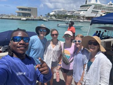 A cheerful group poses for a selfie before embarking on a boat tour, capturing the excitement of their upcoming adventure in a vibrant coastal setting.