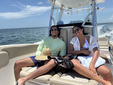 A couple enjoys a sunny day on a boat, relaxing and soaking up the sun — perfect for a day out on the water.