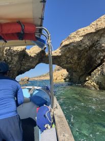 A scenic view of a boat navigating through a natural rock formation, showcasing the beauty of the coastline and the adventure of on-water exploration.