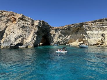 A picturesque view of boats near a stunning coastal cave, showcasing the vibrant blue waters and rocky cliffs — perfect for exploring and enjoying the beauty of nature.