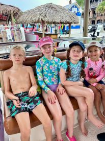 A group of children relaxes on a boat, ready for a fun day on the water. Their colorful swimwear and excited expressions capture the joy of a boating adventure.