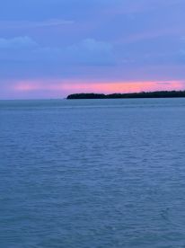 A stunning sunset over the coastline, showcasing vibrant colors reflecting on the water — a perfect backdrop for evening boat trips.
