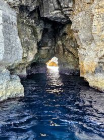 A stunning view of a natural cave opening, with sunlight illuminating the water inside — a picturesque spot for exploration and adventure on the water.