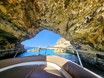 A stunning view from inside a boat looking out through a natural rock arch, showcasing the beautiful turquoise waters and rugged coastline — perfect for exploring hidden gems on the water.