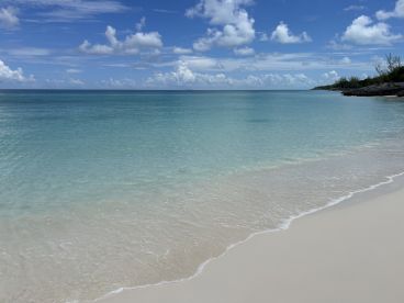 A serene beach scene featuring clear turquoise waters and a sandy shoreline under a bright blue sky, perfect for relaxation and scenic views.