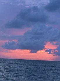 A scenic view of the ocean at sunset, featuring vibrant colors in the sky, though the image lacks clarity.