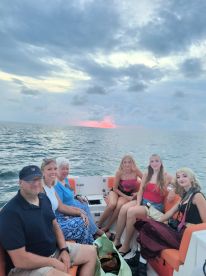 A cheerful group enjoys a sunset boat ride, capturing memorable moments together on the water.