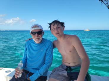 A joyful moment captured with a grandfather and grandson enjoying their time on a boat in the ocean, showcasing the beauty of family bonding on the water.
