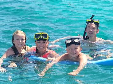 A joyful family enjoys snorkeling together in clear turquoise waters, creating unforgettable memories during their aquatic adventure.