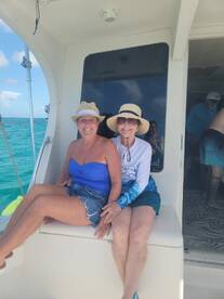 Two friends enjoy a sunny day on a boat, capturing a joyful moment together amidst the beautiful turquoise waters.
