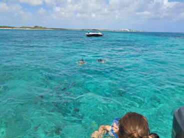 A group enjoys snorkeling in the crystal-clear waters, showcasing the vibrant marine life and a perfect day on the water.