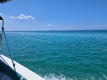 A scenic view from a boat cruising through crystal-clear turquoise waters, showcasing the beauty of the open sea.