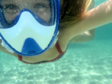 A young snorkeler enjoys an underwater adventure, showcasing the vibrant marine life in crystal-clear waters — perfect for aquatic exploration.