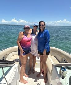 Three friends pose together on a boat under the bright sun, capturing a joyful moment on the water — perfect for summer outings and celebrations.