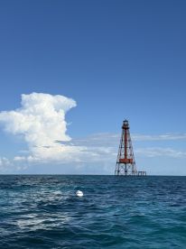 A stunning view of a lighthouse standing tall against a clear blue sky, surrounded by vibrant turquoise waters — a picturesque landmark for boating enthusiasts.
