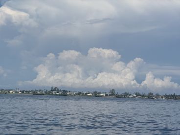 A scenic view of clouds over water, with a distant shoreline visible. The image lacks clarity and detail.