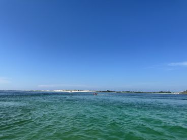 A vibrant view of the coastline with clear turquoise waters, showcasing a perfect day for water activities. The scene captures the essence of a relaxing day on the water.