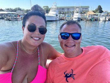 A cheerful couple enjoys a sunny day on the water, capturing a perfect moment while boating at the marina.