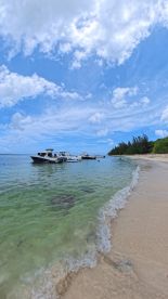 A picturesque beach scene featuring several boats anchored in clear waters, perfect for a relaxing day by the shore.
