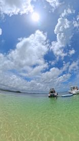 A beautiful day on the water with boats anchored in shallow, clear waters, perfect for swimming and enjoying the sun.