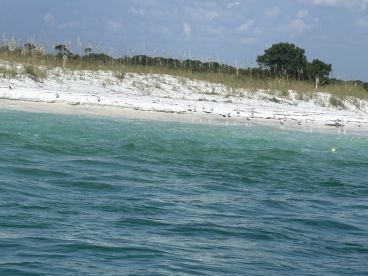 A serene view of a beautiful beach with white sand and turquoise waters, perfect for a relaxing day on the coast.