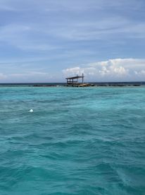 A serene view of a wooden structure on a rocky outcrop surrounded by stunning turquoise waters, perfect for a tranquil getaway or scenic boat tours.