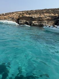 A picturesque view of boats anchored near a rocky coastline, showcasing the stunning clear waters — perfect for exploring hidden coves and enjoying a day on the water.