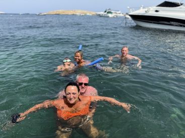 A lively group enjoys a refreshing swim in clear waters, showcasing the fun of snorkeling and aquatic adventures during their boating trip.