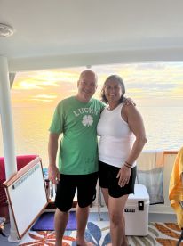 A couple poses together on a boat during a stunning sunset, capturing a moment of joy and celebration on the water.