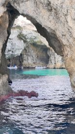 A stunning view of a cave with turquoise waters, featuring boats inside — perfect for exploring scenic coastal landscapes.