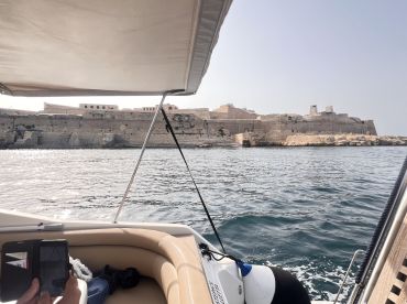 A scenic view from a boat showcasing a historic coastline, with a passenger capturing the moment. Ideal for exploring landmarks and enjoying the beauty of the water.