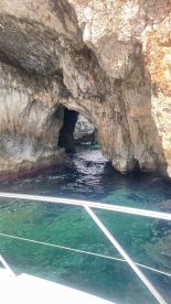 A stunning view of a cave entrance along the coastline, with a boat visible in the background, showcasing the beauty of marine exploration.