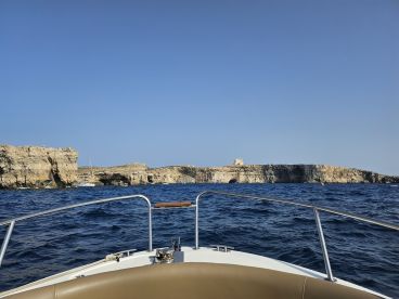 A stunning view from the bow of a boat, showcasing a rugged coastline and distant island, perfect for exploring the beauty of the sea.
