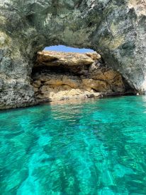 A stunning view of a natural rock arch over crystal-clear turquoise waters, showcasing the beauty of coastal landscapes — perfect for eco tours and scenic boat trips.