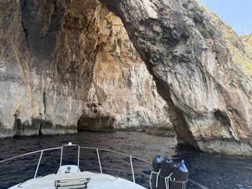 A stunning view of a natural rock arch from the bow of a boat, showcasing the beauty of coastal landscapes and unique geological formations.
