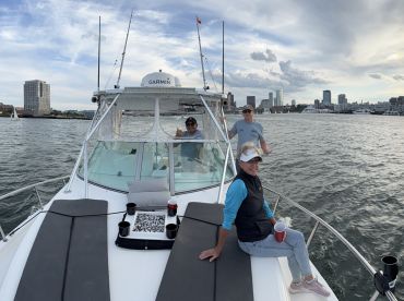 A cheerful group enjoys a day on the water aboard a boat, with stunning city skyline views in the background — perfect for social gatherings and celebrations.