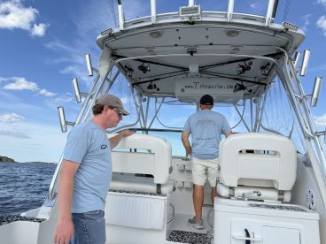 Two individuals are seen inside the helm of a boat, showcasing the interior design and functionality, perfect for navigating the open waters.