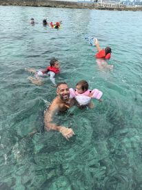 A joyful family enjoys a fun day swimming in clear waters, with children in life jackets and snorkeling gear, creating unforgettable memories together.