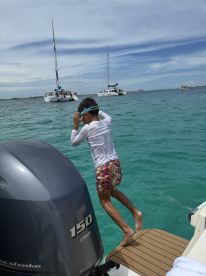 A child prepares to jump into the clear turquoise waters from the boat, capturing the excitement of a fun day on the water, perfect for snorkeling and swimming adventures.